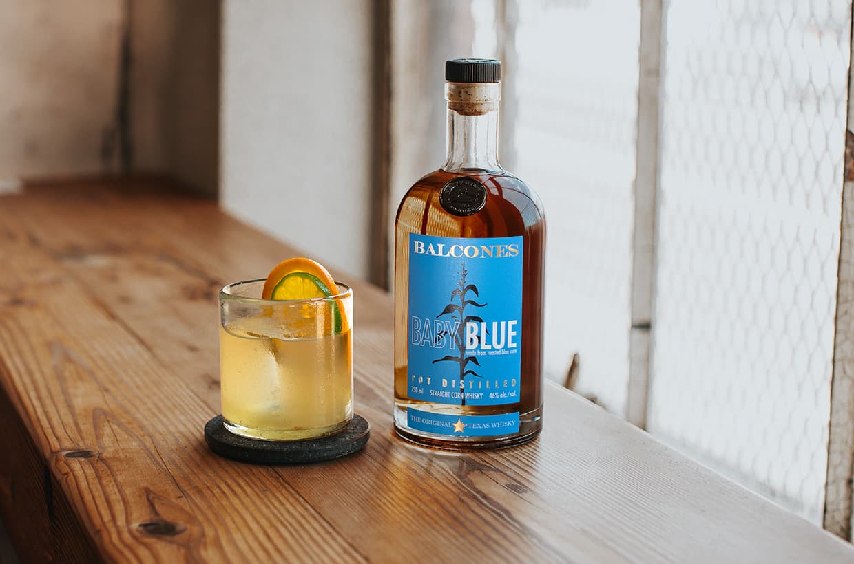 Bottle of Baby Blue with a glass of Baby Blue Imposterita cocktails on table