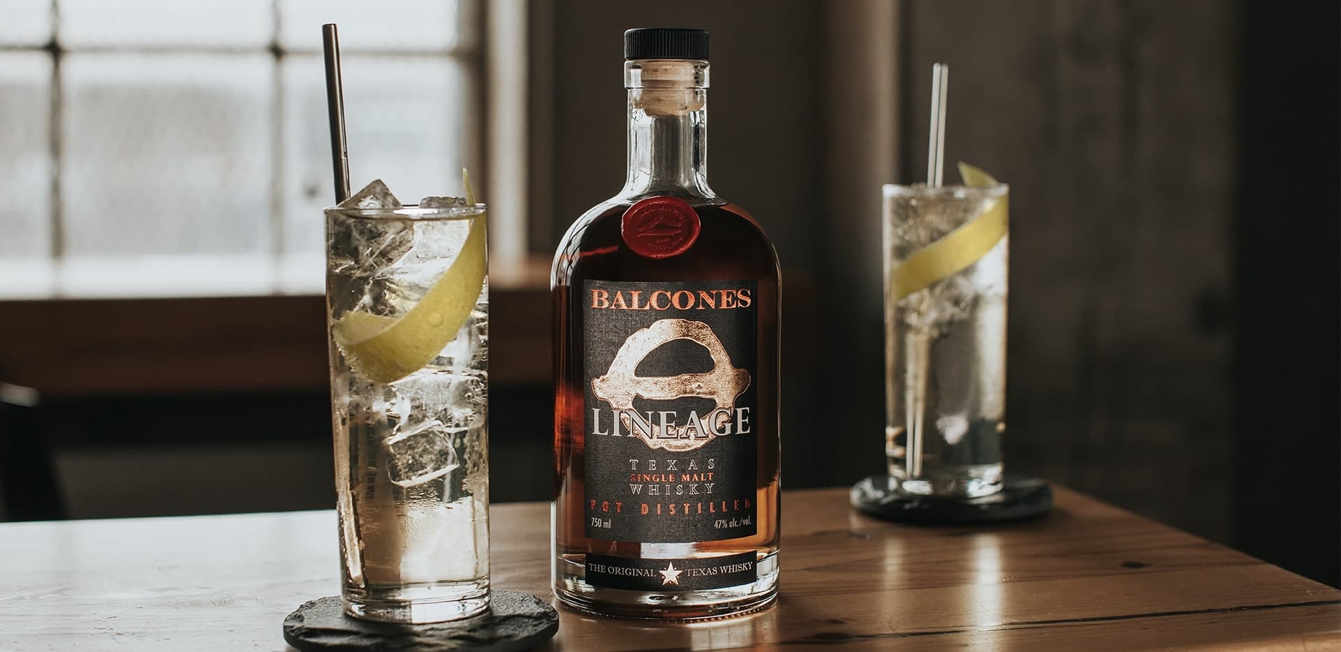 Bottle of Lineage Texas Single Malt Whisky with two glasses of Balcola cocktails