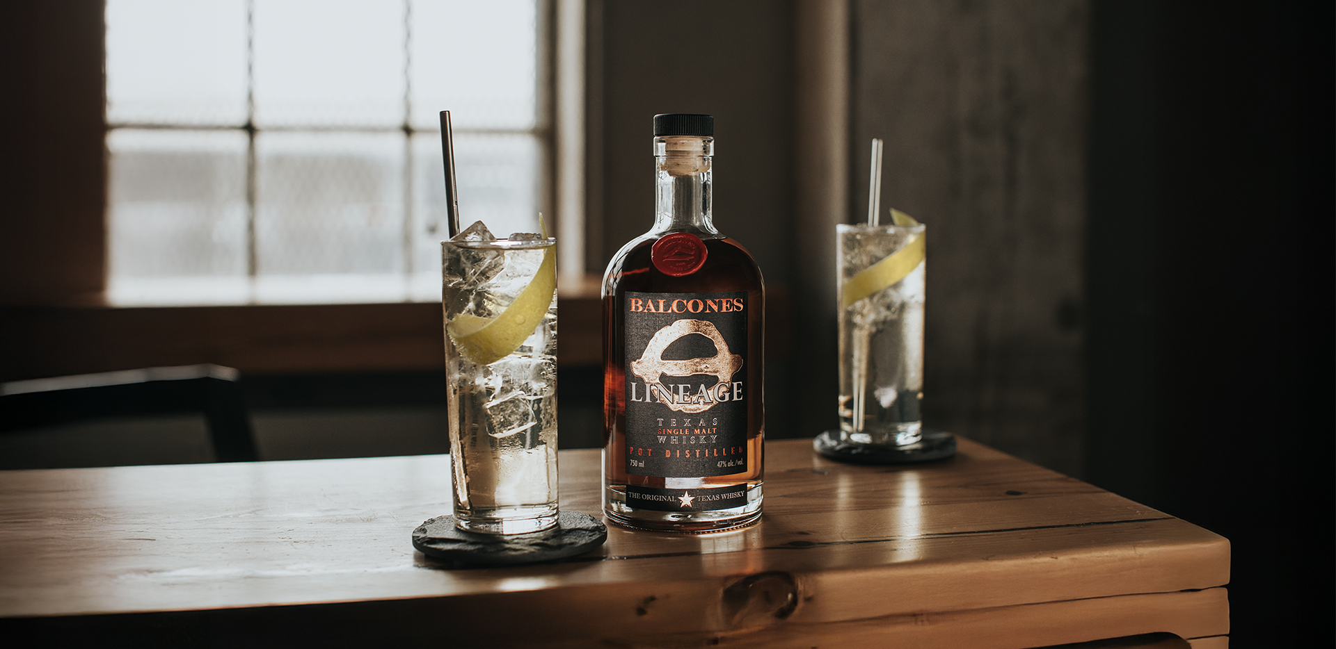 Bottle of Lineage Texas Single Malt Whisky with two glasses of Balcola cocktails