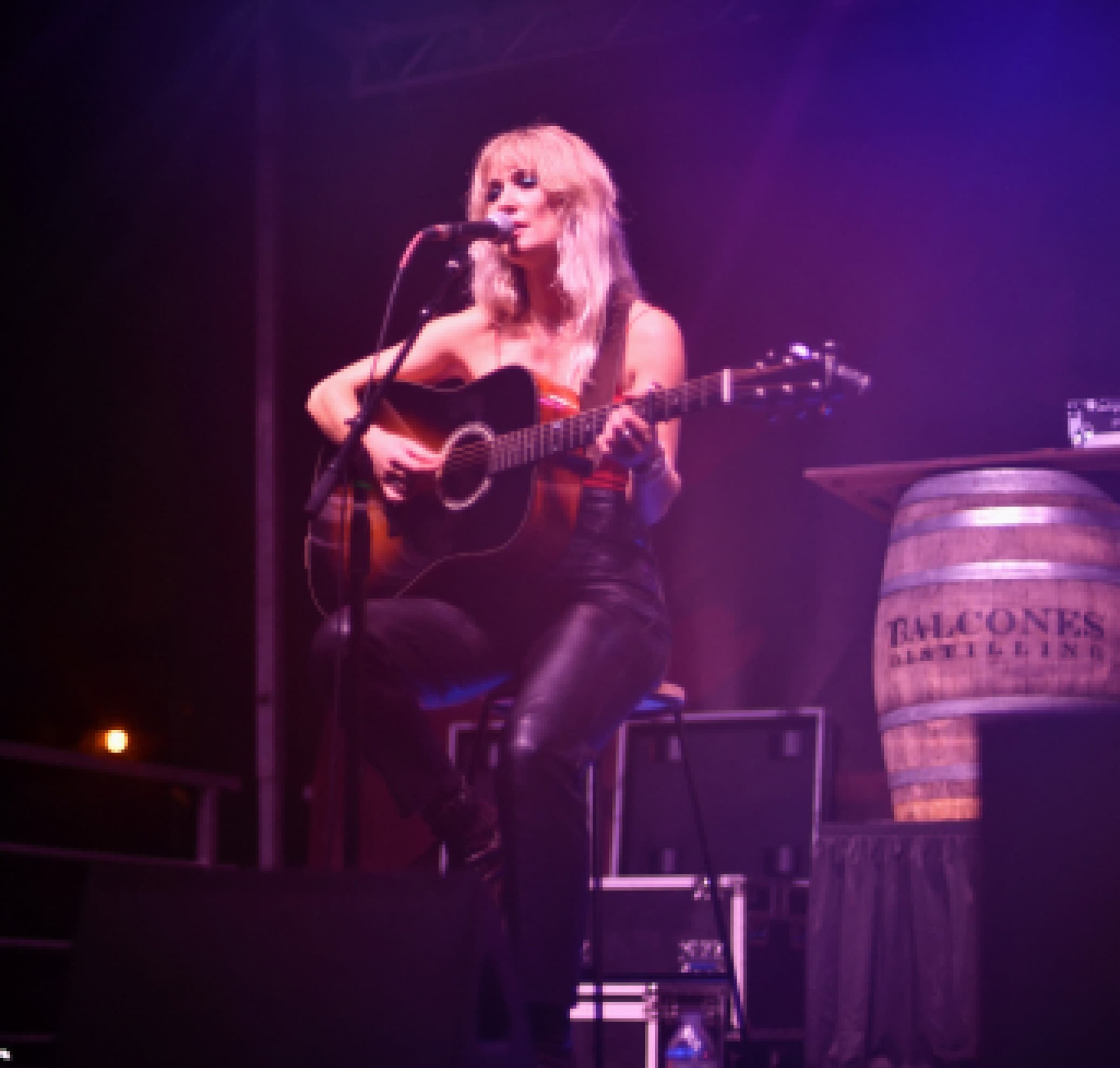 Woman singing and playing guitar on stage