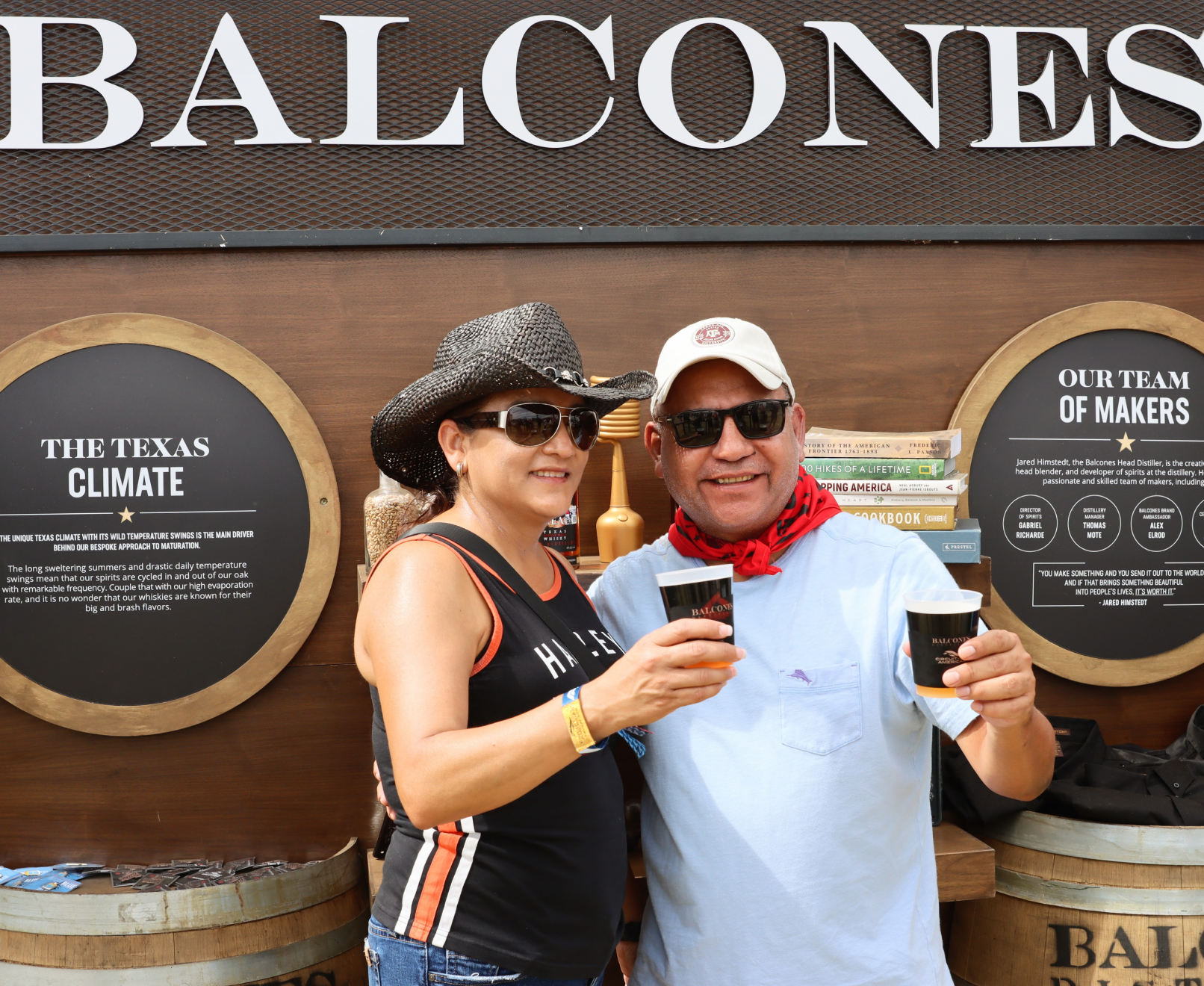 Two people posing in front of Balcones' educational wall