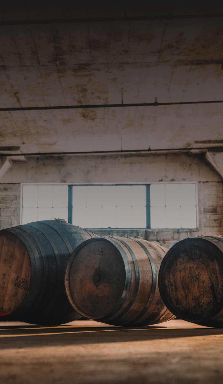 three barrels of varying sizes in the middle of a large room with more barrels against the walls
