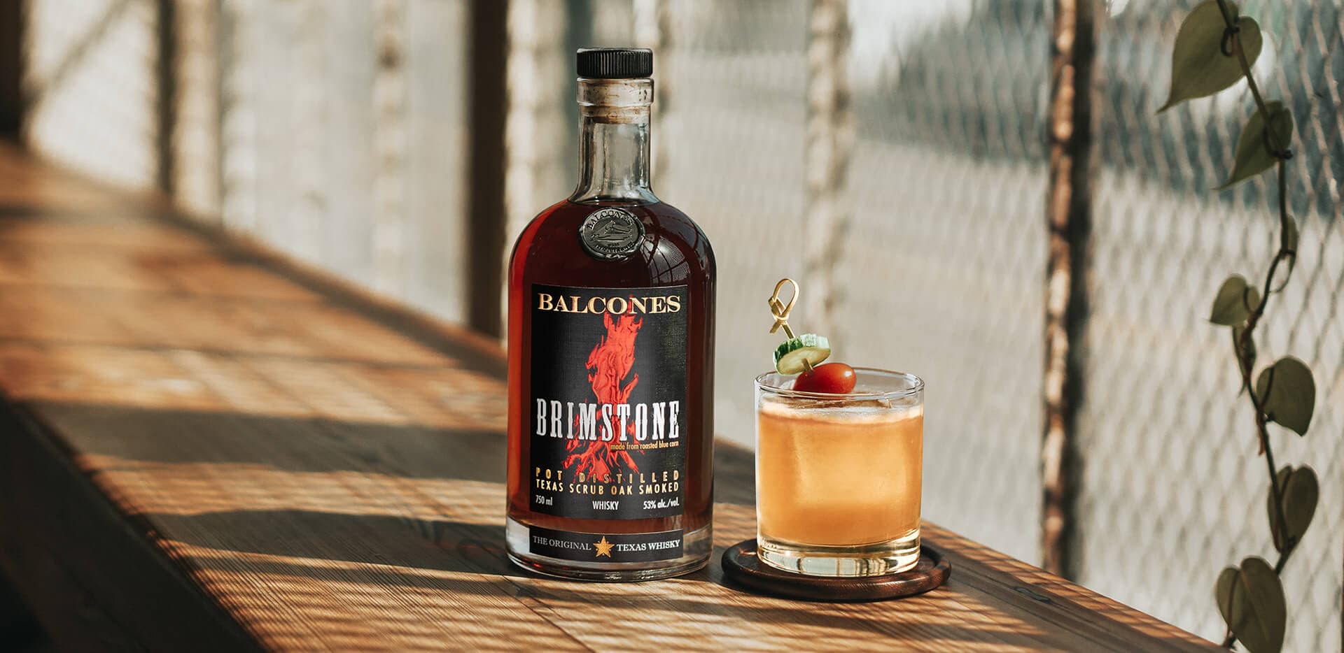 A bottle of Brimstone Smoked Whisky with a Garden Variety cocktail on a table.