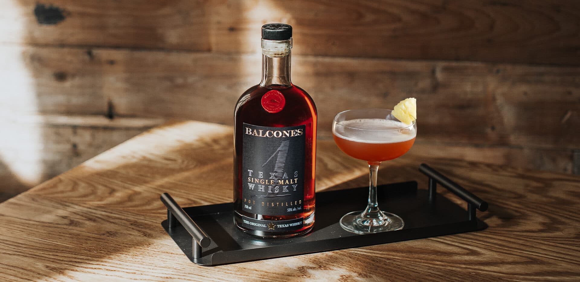 A bottle of Texas 1 Single Malt Whisky with next to a Halekulani cocktail.