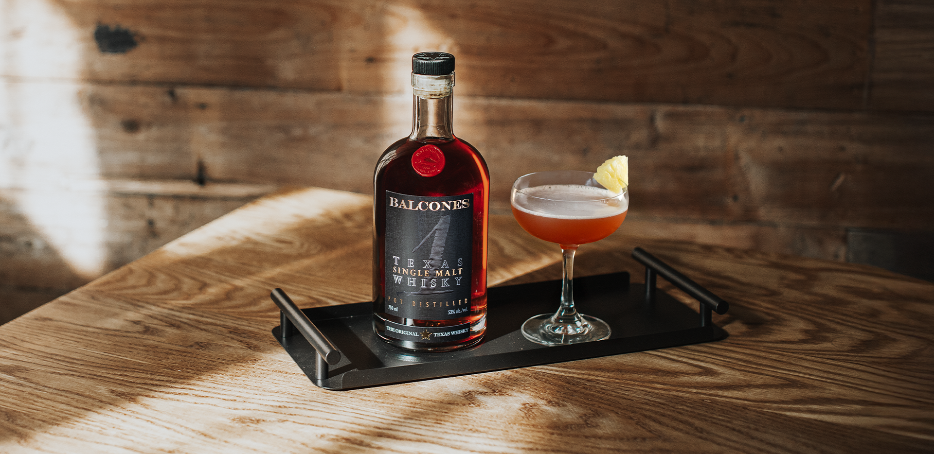 A bottle of Texas 1 Single Malt Whisky with next to a Halekulani cocktail.