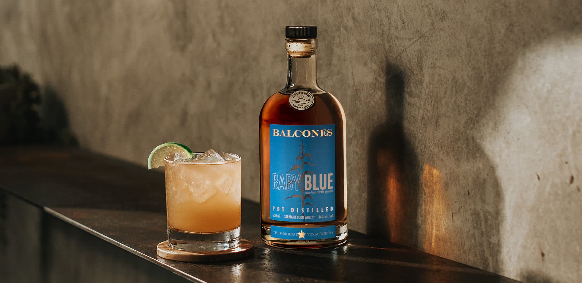 Bottle of Baby Blue with a glass of Baby Blue Imposterita cocktails on table