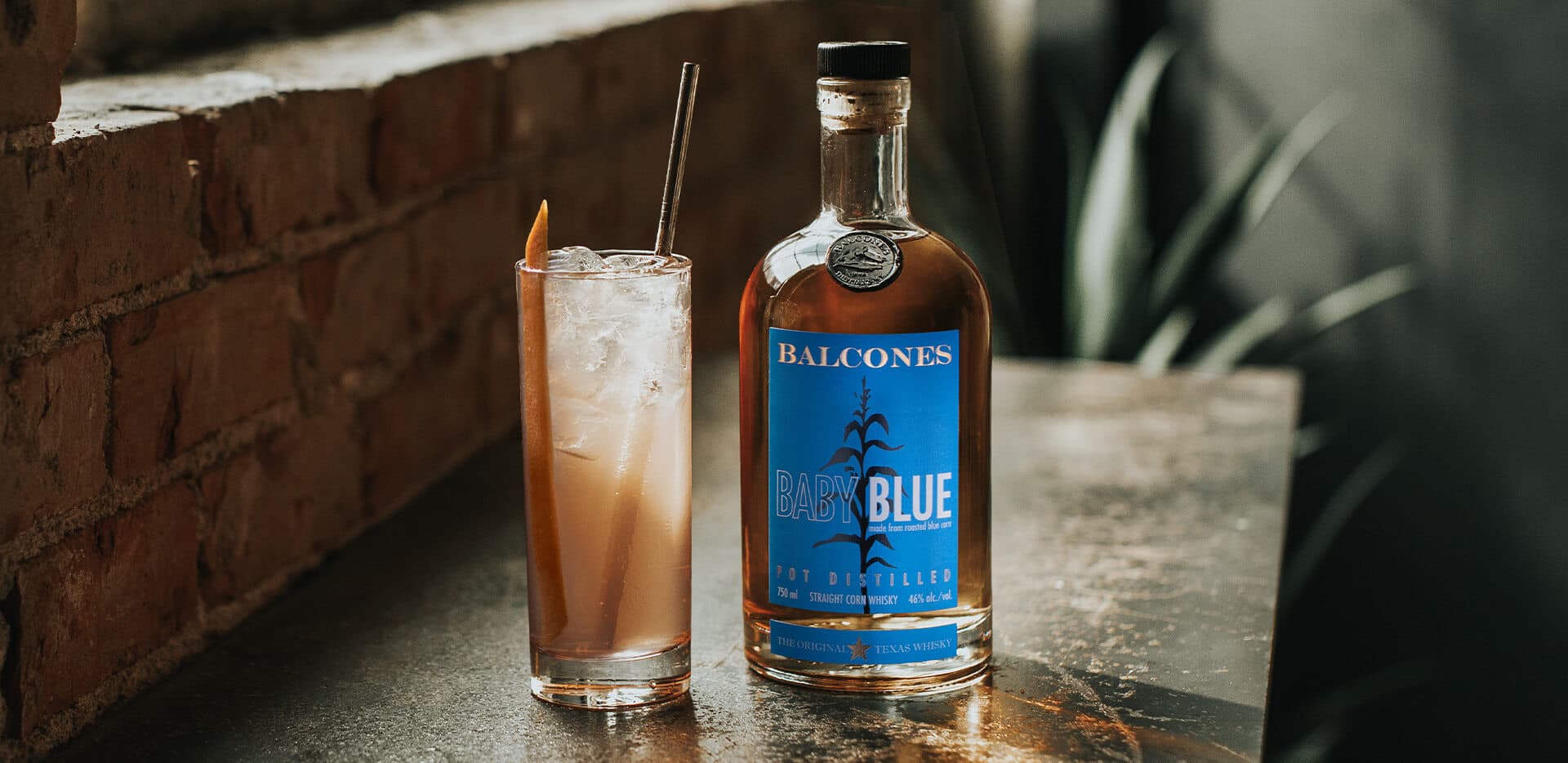 A bottle of Baby Blue Straight Corn Whisky with a glass of Texas Paloma cocktail.