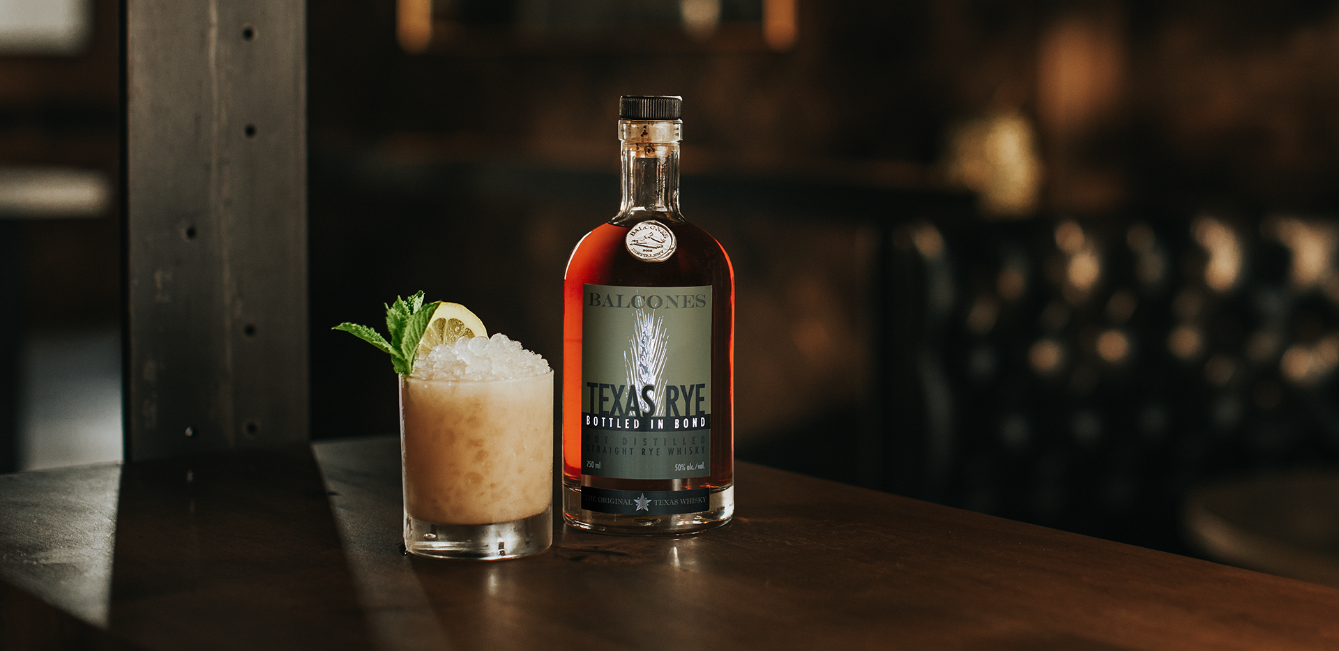 A bottle of Texas Rye Bottled in Bond next to a Texas Rye Tai cocktail on a table.