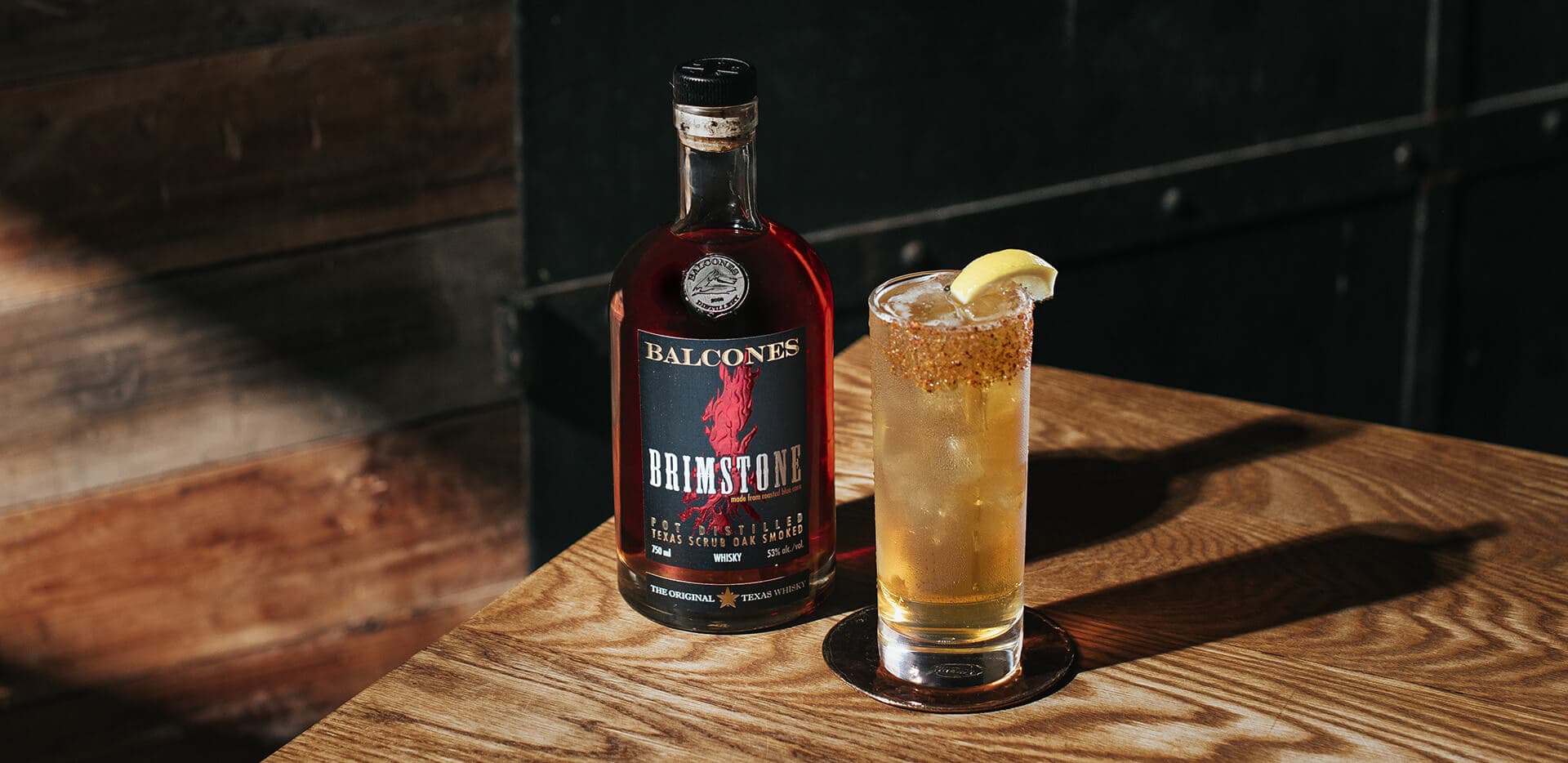 A bottle of Brimstone Smoked Whisky with a Texas Tonic cocktail on a table.
