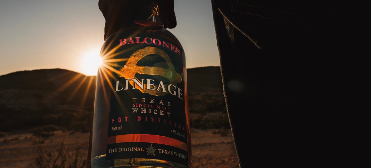 Bottle of Lineage Texas Single Malt Whisky with Texas landscape